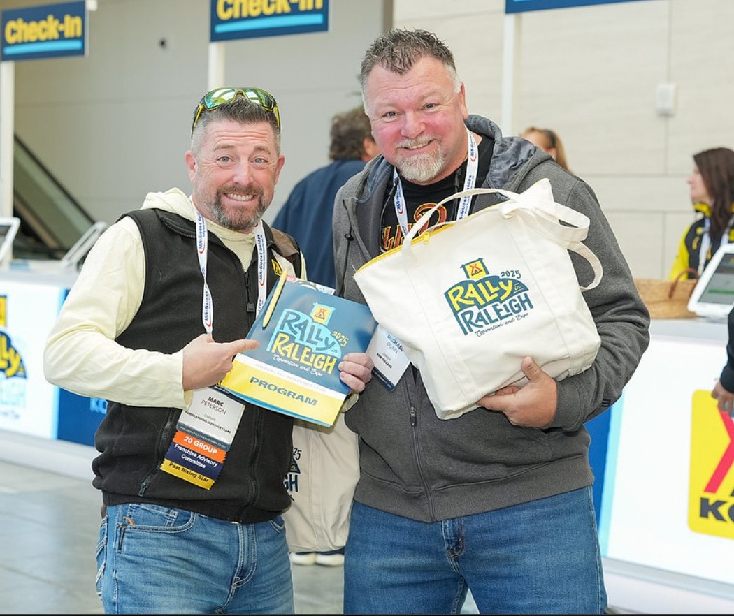 Two KOA owners at the convention check-in desk holding their programs and tote bags